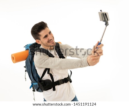 Portrait of young backpacker taking a selfie with his mobile phone isolated on white background. In traveling around the world, staying connected, tourism and social network, living the dream concept.