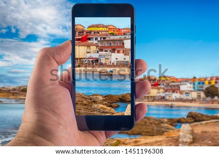 Hand taking picture with a smartphone on the beach inside the village of Porto Torres, Sardinia