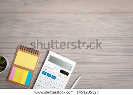 Calculator and open notepad close up on wooden desk