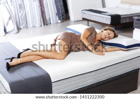  adult girl testing quality of new mattress for bed in salon