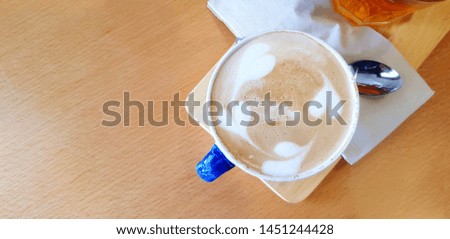 Top view cup of hot latte art in heart or leaves style with tea spoon and glass of water on brown wooden table with left copy space - Refreshment drinking and Food design concept 