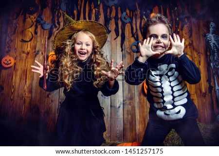 Portrait of a cute funny kids posing with pumpkins on a hay. Happy Halloween!