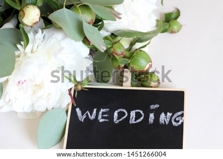 Wedding calligraphy template text for your design illustration concept. Handwritten lettering title words on  black isolated background. White peonies on a light background stock photo
