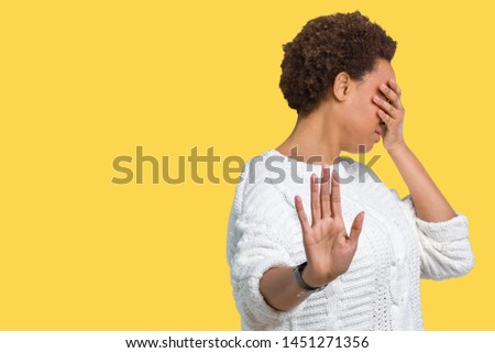 Beautiful young african american woman wearing sweater over isolated background covering eyes with hands and doing stop gesture with sad and fear expression. Embarrassed and negative concept.