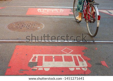 Cyclist ride bicycle cross the light rail track and red painted caution tram sign and symbol on asphalt road in downtown city Düsseldorf, Germany.