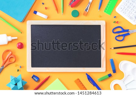 Assorted office and school red green blue and white stationery on yellow background with black board. Flat lay copy space for back to school or education development and craft concept. frame