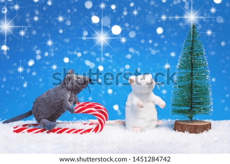 Two toy mice on Christmas candy cane sledges and festive tree and snow. Year of the rat greeting card, Chinese style new year with copy space