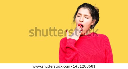 Young beautiful woman wearing red sweater and bun bored yawning tired covering mouth with hand. Restless and sleepiness.