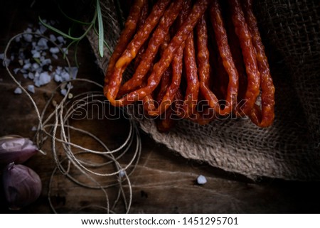 Sausage dry sausages. Thin sausages with herbs on a dark background