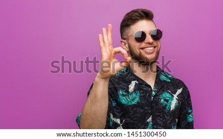 Young man wearing a vacation look cheerful and confident showing ok gesture.
