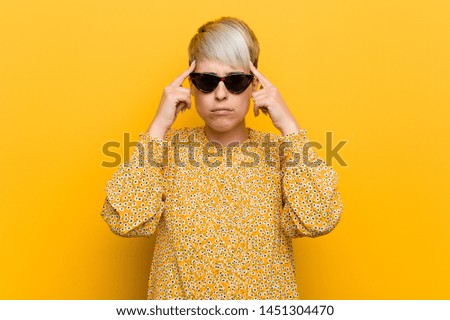Young curvy woman wearing a floral summer clothes focused on a task, keeping forefingers pointing head.