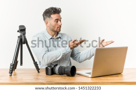 Young handsome photography teacher holding a copy space on a palm.