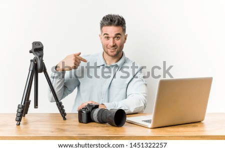 Young handsome photography teacher person pointing by hand to a shirt copy space, proud and confident