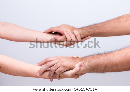 A man and a woman holding hands in sign of cooperation, strength and welcome on a neutral background