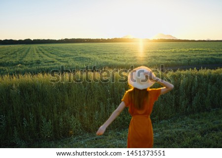 Beautiful woman in a red dress on the nature look at the sun