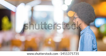 Young african american man with afro hair wearing thug life glasses looking to side, relax profile pose with natural face with confident smile.
