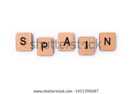 The word SPAIN, spelt with wooden letter tiles, over a white background.