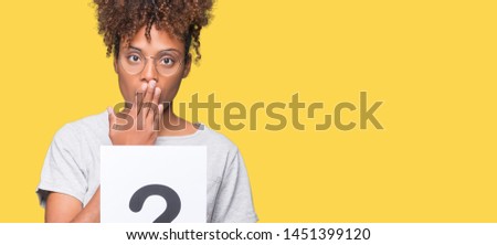 Young african american woman holding paper with question mark over isolated background cover mouth with hand shocked with shame for mistake, expression of fear, scared in silence, secret concept