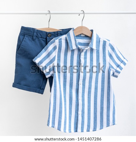 Blue shirt with stripes and shorts for a boy hanging on shoulders isolated on white background. Baby clothes Royalty-Free Stock Photo #1451407286