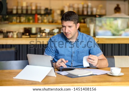Mature restaurant owner calculating finance and bills of new business  – Entrepreneur online using tablet and calculator to work and calculate financial expenses of small coffee shop business start-up Royalty-Free Stock Photo #1451408156