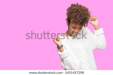Beautiful young african american woman wearing winter sweater over isolated background Dancing happy and cheerful, smiling moving casual and confident listening to music