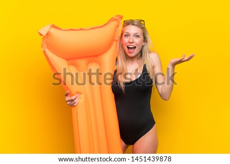Young woman in swimsuit over yellow background with surprise and shocked facial expression
