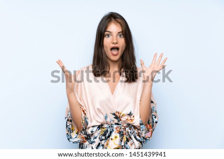 Caucasian girl with kimono over isolated blue background with surprise facial expression