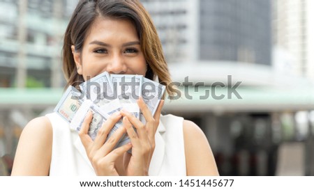 Successful beautiful Asian business  woman holding money US dollar bills in hand , business concept