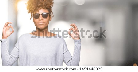 Beautiful young african american woman wearing sunglasses over isolated background relax and smiling with eyes closed doing meditation gesture with fingers. Yoga concept.