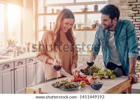 Real love. Beautiful young couple cooking dinner and drinking wine while standing in the kitchen at home Royalty-Free Stock Photo #1451449193