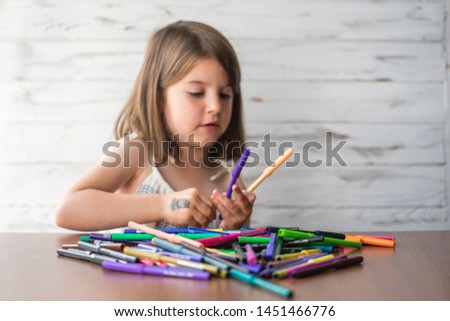 Portrait of beautiful thoughtful little girl with pencils, daydreaming and creating picture ideas in her mind. Creative process. Education and school concept. Selected focus
