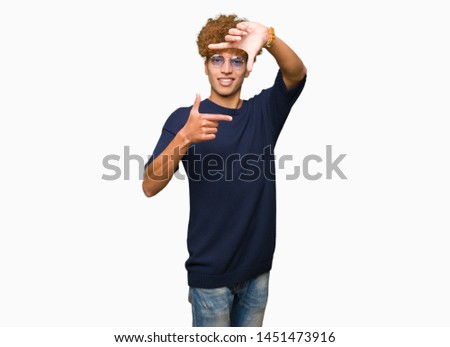 Young handsome man with afro wearing glasses smiling making frame with hands and fingers with happy face. Creativity and photography concept.
