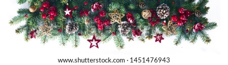 Festive Christmas border, isolated on white background. Fir green branches are decorated with gold stars, fir cones and red berries. Close-up.