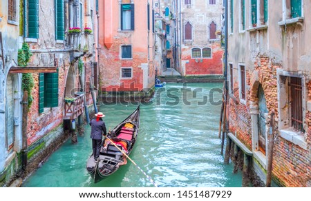 Venetian gondolier punting gondola through green canal waters of Venice Italy Royalty-Free Stock Photo #1451487929