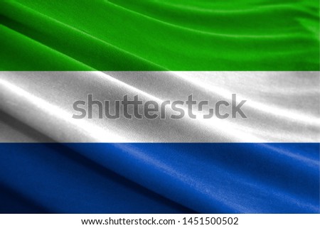 Realistic flag of Sierra Leone on the wavy surface of fabric