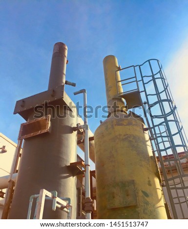 Old two exhaust scrubber chimney and ladder for factory, this tower use for air treatment almost in chemical industry,reduce air pollution in the environmental,with clear blue sky and daylight.