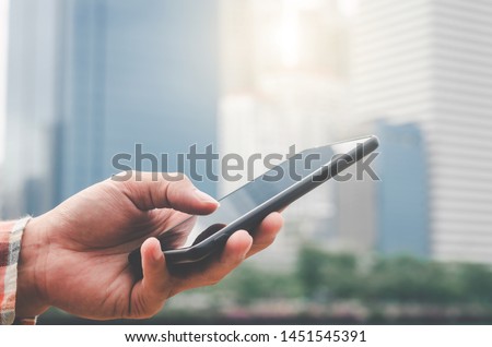 close up handsome man using hand typing mobile phones and touch screen working search with app devices outdoor in city with sunrise and building background.