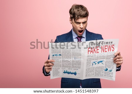 shocked businessman reading newspaper with fake news on pink background