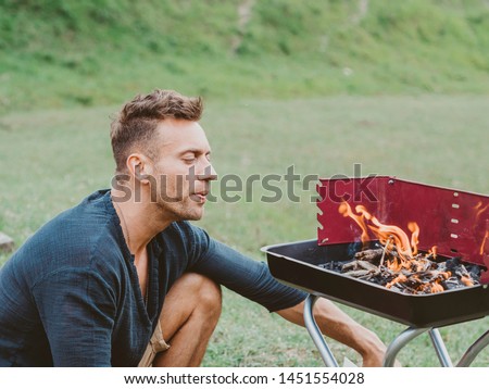 Young man doing a barbecue in the countryside