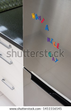 "have a nice day" sign created by magnetic letters on silver door of fridge.