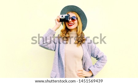 Portrait close-up happy smiling woman holding retro camera taking picture wearing pink coat and hat