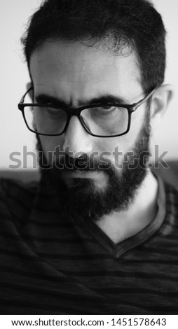 Black and white extreme close up portrait of a  man with serious facial expression. Male showing no emotion looking down on a white background. Vertical photo