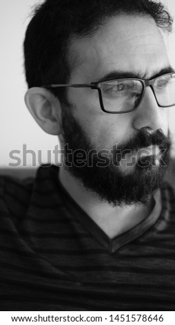 Black and white extreme close up portrait of a  man with serious facial expression. Male showing no emotion looking  left on a white background. Vertical photo