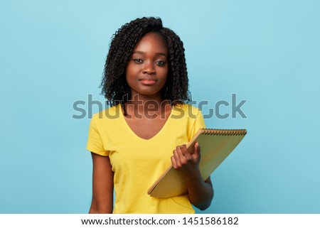 clever beautiful afro female student in yellow stylish T-shirt looking at the camera. paperwork, education, job, profession. close up portrait.
