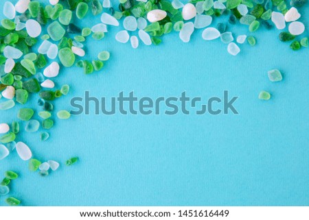 Close up of various sea glass pieces on blue background. Design template. Corner frame with copy space for text. Top view, flat lay