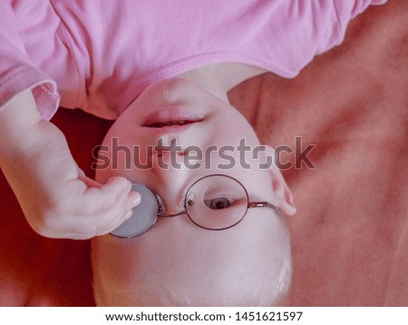 Portrait of funny child in new glasses with patch for correcting squint on pink background. boy playing with red bal 
Ortopad Boys Eye Patces nozzle for glasses for treating strabismus (lazy eye)