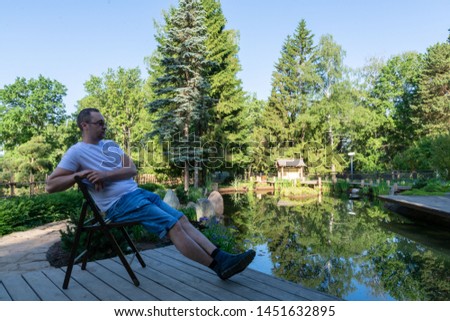 A young man meets a dawn sitting on a wooden folding chair with his legs crossed