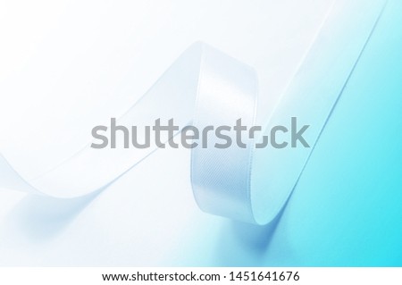Shiny satin ribbon on a white background with a blue gradient