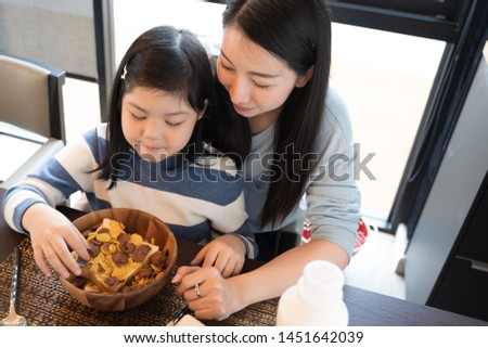 mom and daughter eating Cereals with milk having breakfast in kitchen.