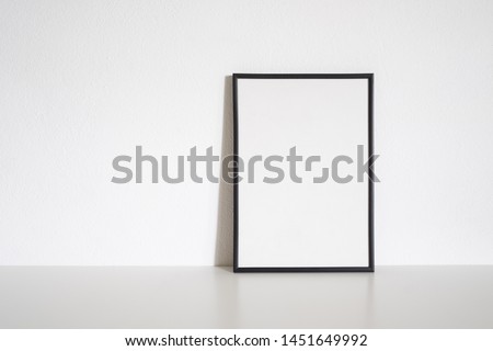 Black frame poster on table in white room